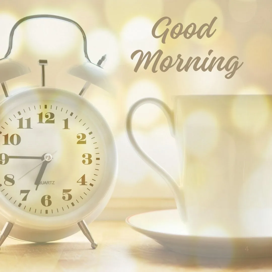Peaceful Morning Still Life – Clock and Coffee with Good Morning Text White alarm clock and coffee cup on wooden surface with glowing bokeh and “Good Morning” text